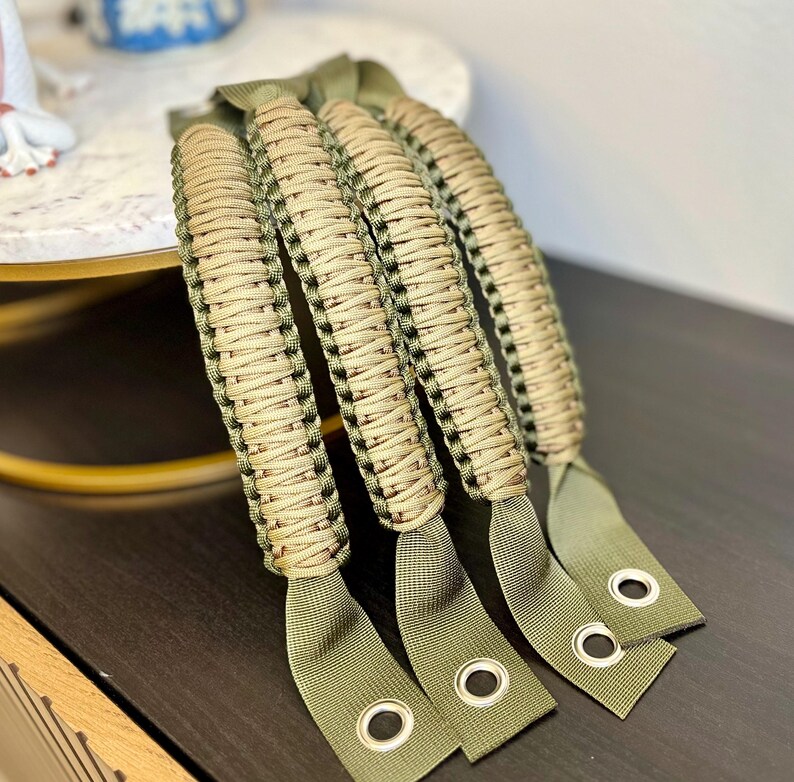 May include: Four green and tan paracord handles with metal eyelets. The handles are braided and have a textured look.