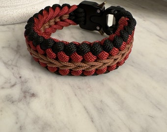 May include: A black, brown, and red paracord bracelet with a black plastic buckle.