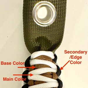 May include: A close-up of a paracord bracelet with a green strap, brown base color, white main color, and black edge color.