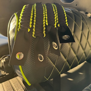 May include: Four black and green paracord straps with metal eyelets attached to a black and green quilted seat.