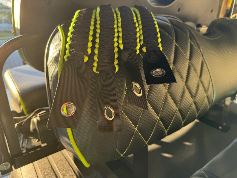 May include: Four black and green paracord straps with metal eyelets attached to a black and green quilted seat.