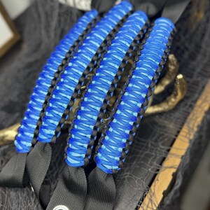 May include: Set of four blue and black paracord jeep door handles. The handles are made with a braided paracord and have black straps with metal rings.