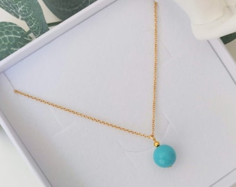 May include: A gold chain necklace with a turquoise blue bead pendant.
