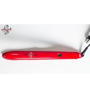 May include: A red hair straightener with the text "TRUST THE PROCESS" in white. The straightener has a rounded tip and a small digital display. A black power cord is attached.