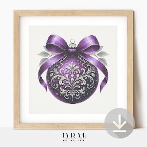 Puede incluir: Un diseño de punto de cruz enmarcado con una bola de Navidad morada con un patrón plateado decorativo. El adorno está adornado con un lazo a juego y hojas plateadas. El diseño está sobre un fondo blanco.