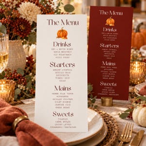 May include: Two vertical menu cards featuring dark red text and a small pumpkin illustration. One card is white, the other is dark red. Both list sections for Drinks, Starters, Mains, and Sweets with specific food and beverage items printed below.