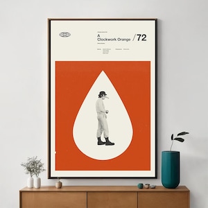 May include: A framed poster featuring a stylized image from the film "A Clockwork Orange." The poster has a bold orange background with a white teardrop shape containing a figure in black and white. Text at the top reads "A Clockwork Orange /72."