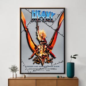 May include: Framed poster for the film "Heavy Metal". The artwork shows a woman riding a winged creature, with the title in blue and silver. The tagline reads "Louder and Nastier Than Ever!"