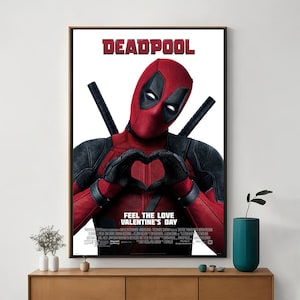 Puede incluir: Un póster de película para la película Deadpool, con Deadpool en un traje rojo y negro haciendo un corazón con sus manos. El póster tiene el texto "Deadpool" y "Feel the Love Valentine's Day".