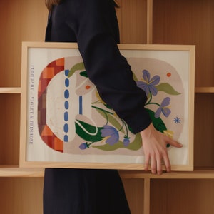 May include: A framed print with a colorful abstract design featuring flowers, geometric shapes, and the text "FEBRUARY - VIOLET & PRIMROSE".