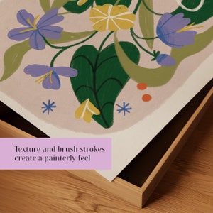 May include: A framed print with a floral design featuring purple, yellow, and green flowers on a light pink background. The print has a painterly feel with visible brushstrokes.
