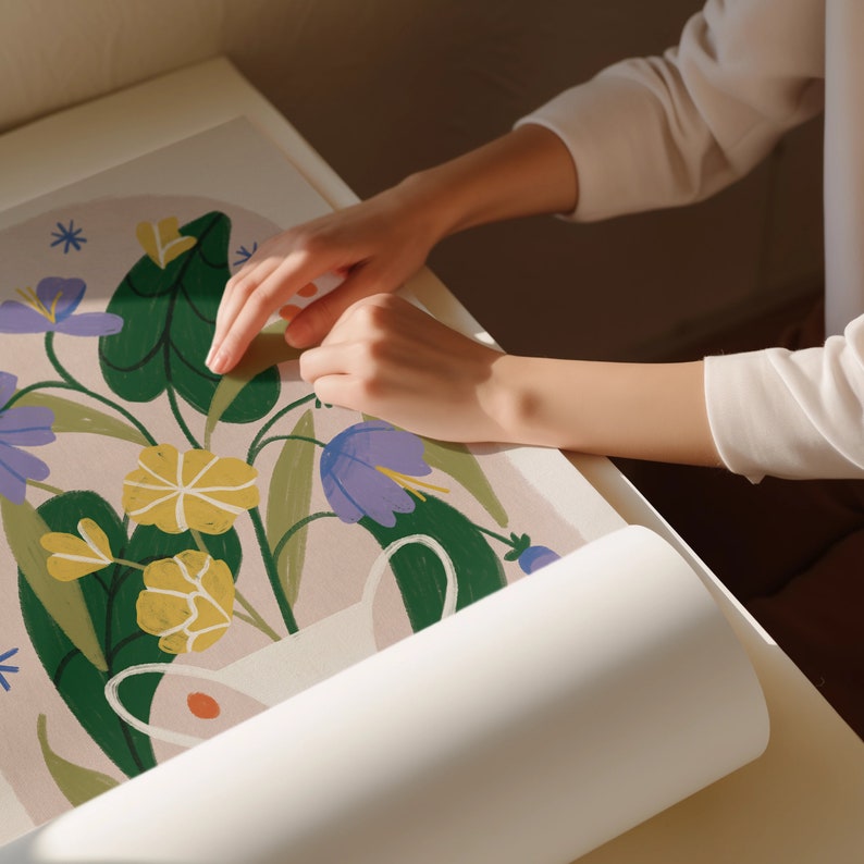 May include: A white poster with a floral illustration featuring yellow, green, and purple flowers. The poster is rolled up and being held by a person's hand.