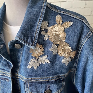 May include: A blue denim jacket with gold and silver sequins embroidered on the shoulder.