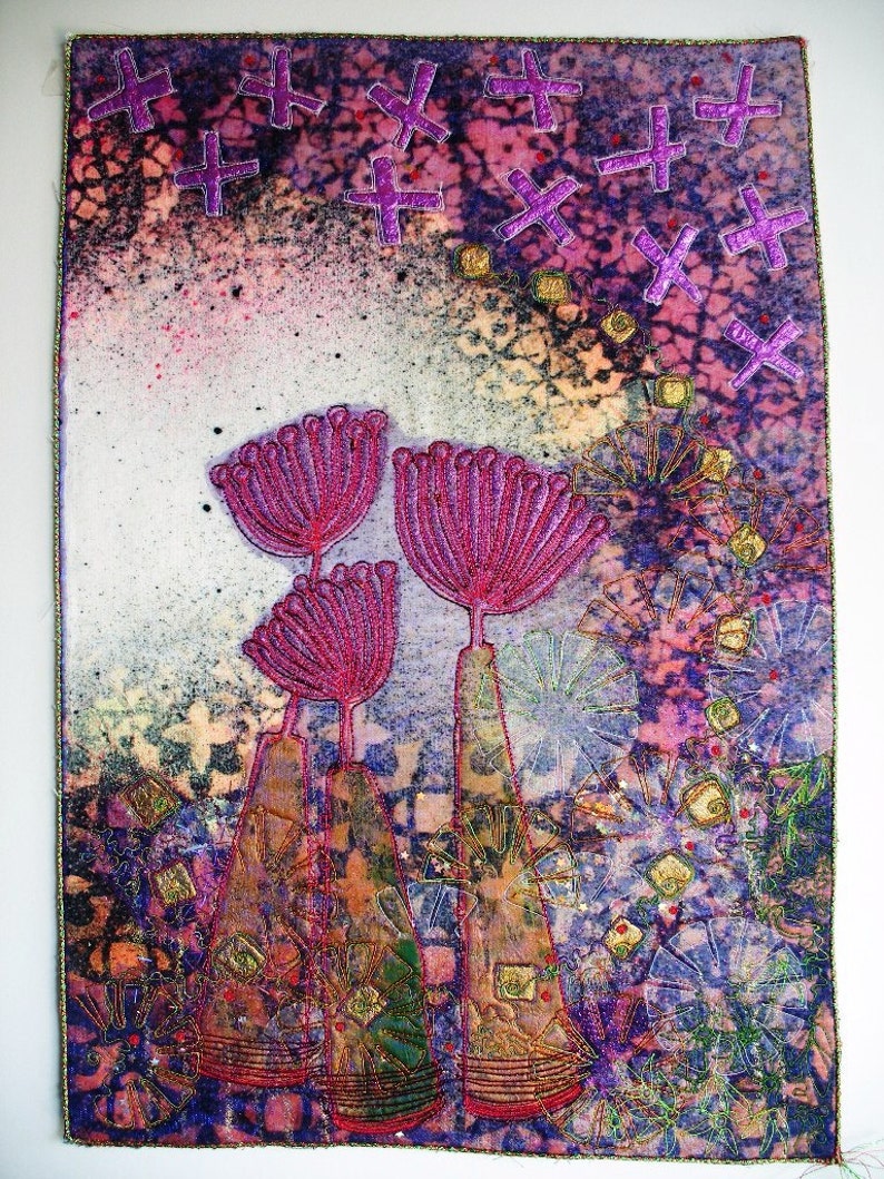 Pu&ograve; includere: Un'opera d'arte tessile colorata con uno sfondo strutturato e tre forme di fiori rosa. Lo sfondo &egrave; un mix di viola, rosa e bianco con un motivo di piccole croci. Le forme dei fiori sono fatte di tessuto e hanno un aspetto tridimensionale.