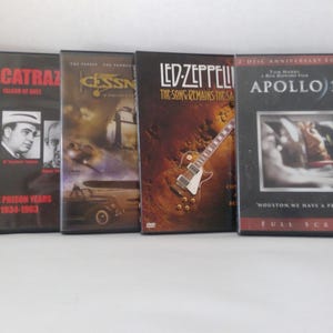 May include: Four DVD movie cases are displayed, featuring titles like "Alcatraz: Island of Evil," "Cessna," "Led Zeppelin: The Song Remains the Same," and "Apollo 13." The cases are black with various images and text, including movie titles and actors.