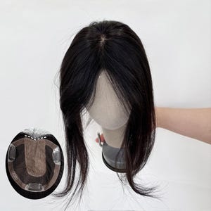 Puede incluir: Una pieza de cabello castaño oscuro con una línea de cabello natural. La pieza capilar tiene una ligera onda y está sujeta a una pequeña base circular con clips. Diseñada para añadir volumen y cobertura.