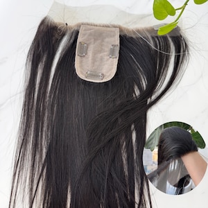 以下が含まれることがあります： 小さなベージュ色のベースと3つのクリップが付いた黒髪のヘアトッパー。髪は長くストレートで、自然な見た目です。このトッパーは、髪にボリュームとカバー力を加えるように設計されています。