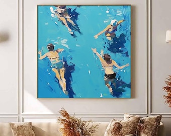 May include: An abstract painting depicts four figures swimming in a bright blue pool. The artwork, framed in gold, hangs above a beige sofa with decorative pillows. The room is decorated with neutral tones and modern furniture.