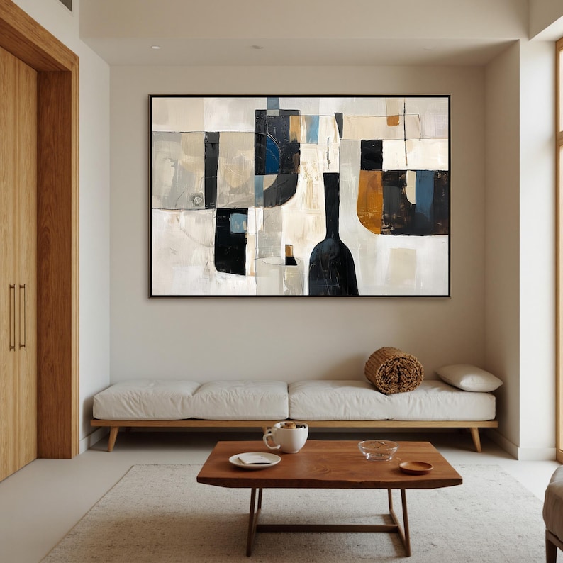 May include: Abstract art piece in a black frame. The artwork features a geometric design with shapes in black, white, beige, and blue. The painting hangs above a white sofa and a wooden coffee table.