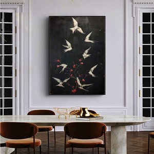 May include: A black and white painting of a flock of white birds flying around a branch with red blossoms against a dark background.