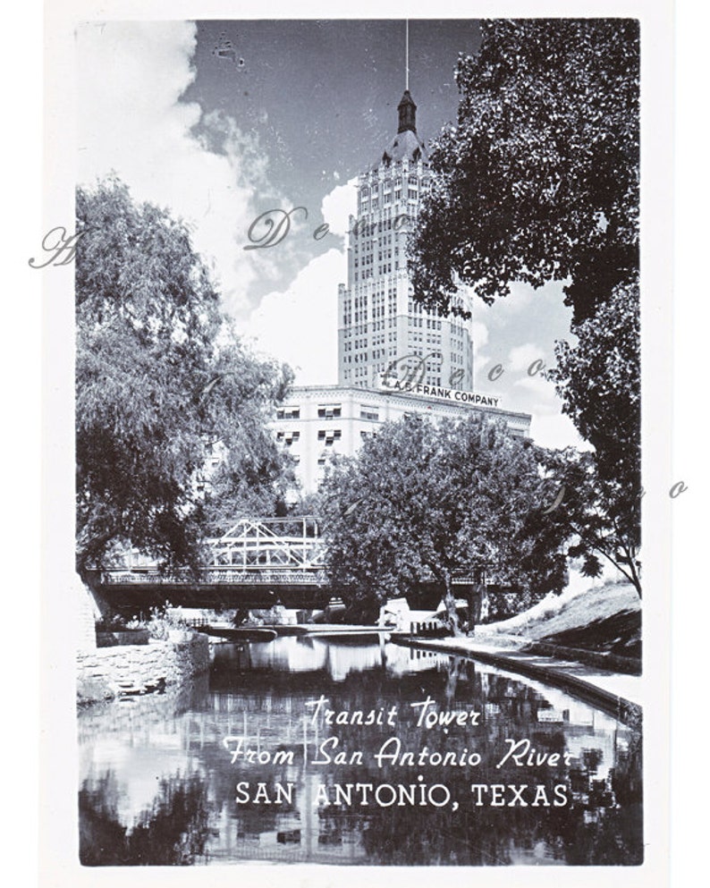 May include: A black and white vintage postcard depicting the Transit Tower in San Antonio, Texas. The tower is viewed from across the San Antonio River, with a bridge in the foreground.