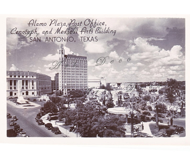 May include: A black and white vintage postcard depicting a view of Alamo Plaza in San Antonio, Texas. The postcard shows the Post Office, Cenotaph, and the Medical Arts Building. The postcard also shows a street with cars and trees.