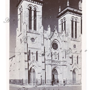 May include: A black and white photograph of San Fernando Cathedral in San Antonio, Texas. The cathedral has two tall towers with arched windows and a large, round rose window.