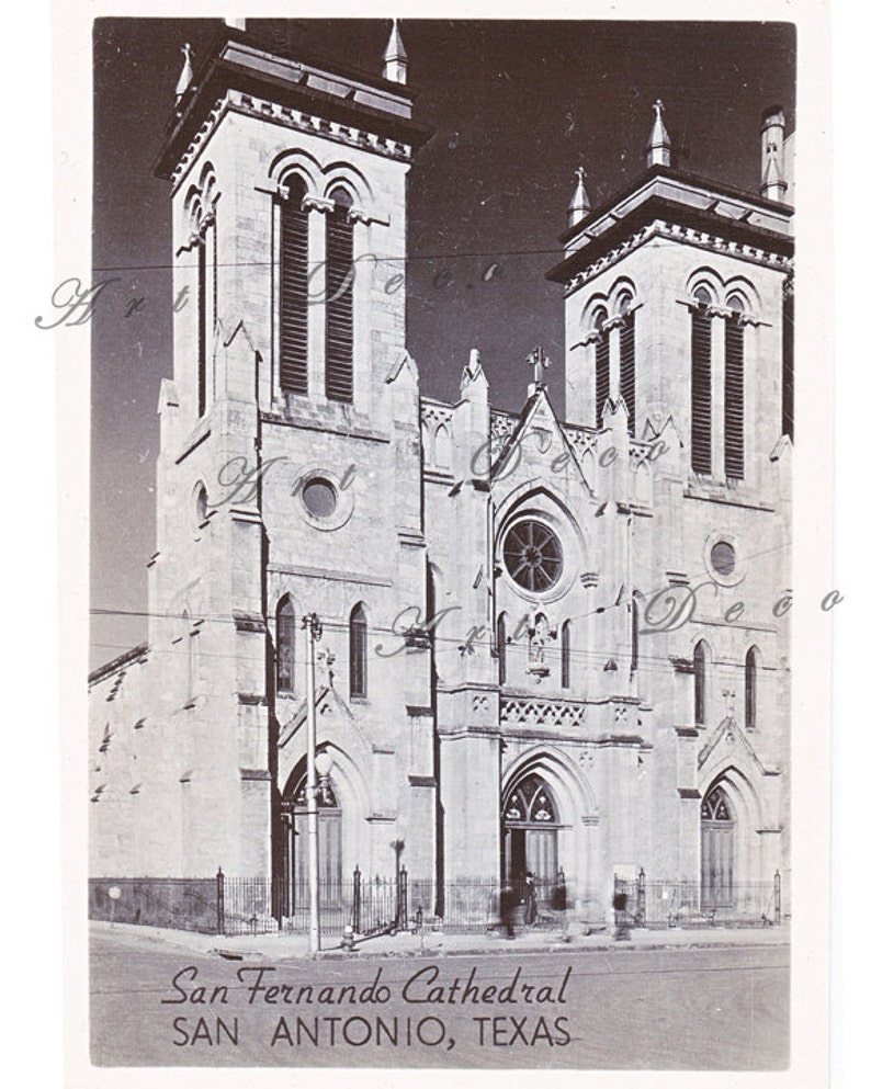May include: A black and white photograph of San Fernando Cathedral in San Antonio, Texas. The cathedral has two tall towers with arched windows and a large, round rose window.