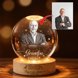 May include: A crystal ball with a portrait of a man, the word "Grandpa", and the years 1953-2025 etched on it. The wooden base has the inscription "Those we love don't go away, they walk beside us every day."