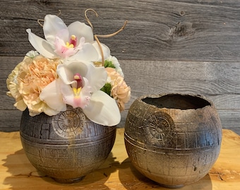 Könnte beinhalten: Zwei graue Keramikvasen in Form des Todessterns aus Star Wars, eine mit einem Strauß weißer Orchideen und pfirsichfarbener Nelken.