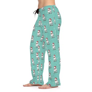 May include: Light blue pajama pants with a repeating pattern of white dogs wearing Santa hats. The pants have a drawstring waist and a relaxed fit, perfect for lounging. The dogs are depicted with a festive holiday theme.