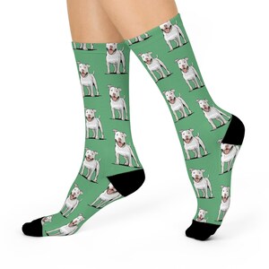 May include: A pair of green socks with a white pit bull terrier pattern. The socks are crew length and have a black toe and heel.