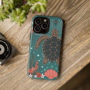 May include: A teal phone case featuring a sea turtle design. The case has a detailed illustration of a turtle, coral, starfish, and flowers. The case is on a wooden surface.