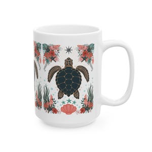 May include: White ceramic mug featuring a sea turtle design. The design includes a dark teal turtle, red flowers, starfish, and a seashell. The mug has a large handle and is suitable for hot or cold beverages.