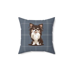 May include: Square throw pillow featuring a cartoon illustration of a Chihuahua dog with brown and white fur. The dog is sitting on a brown oval against a blue plaid background. The pillow is a decorative item.