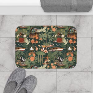 May include: A rectangular bath mat featuring a dark green background with a repeating pattern of white cranes, orange flowers, tropical palm trees, small houses, boats, and figures in motion. The design includes various birds and lush foliage.