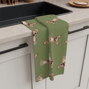 May include: Green kitchen towel with a repeating pattern of brown and white cartoon chihuahua dogs.