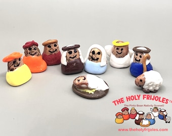 May include: A nativity scene made of pinto beans, featuring the baby Jesus, Mary, Joseph, three wise men, an angel, a shepherd, and a sheep. The scene is titled "The Holy Frijoles" and includes the tagline "The Pinto Bean Nativity Scene".