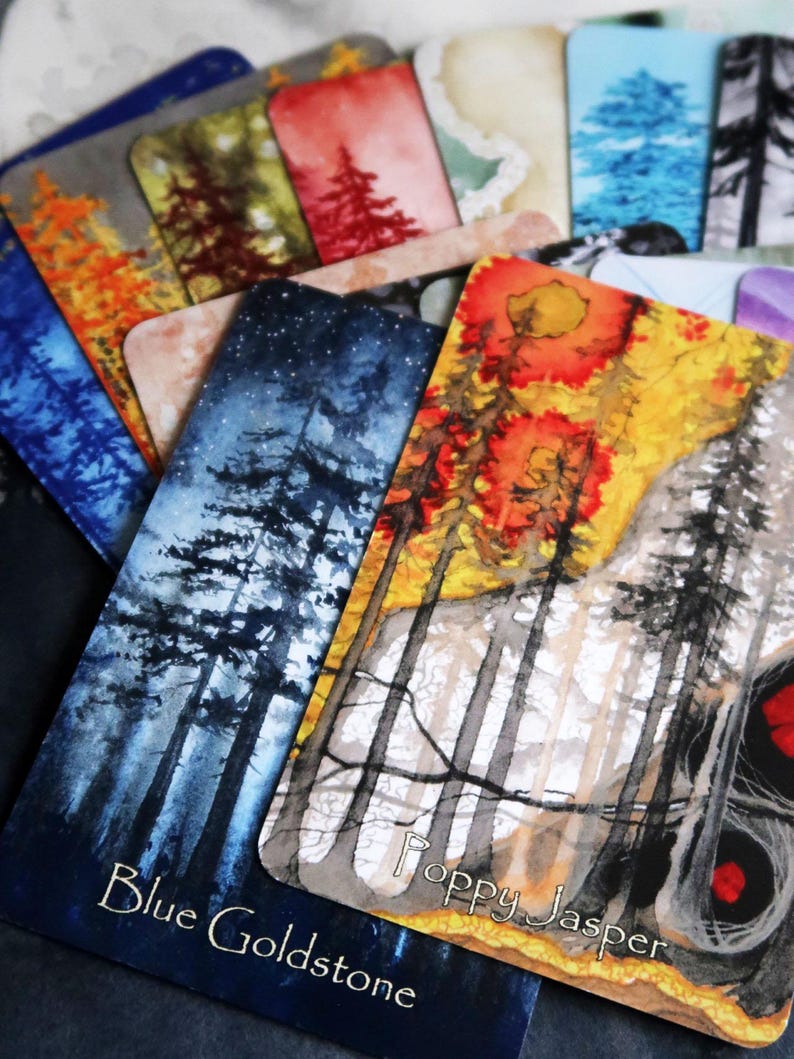 May include: A selection of rectangular cards with watercolour illustrations of trees in various colours. The cards feature names like "Blue Goldstone" and "Poppy Jasper". The artwork includes shades of blue, orange, red, and green.