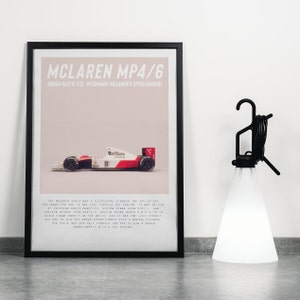 May include: A black and white framed poster with a white background and the text "McLaren MP4/6" in black. The poster features a white and red race car with the text "Marlboro" on the side. The text below the car reads "Honda RA121E V12 - Weismann/McLaren 6-speed manual".