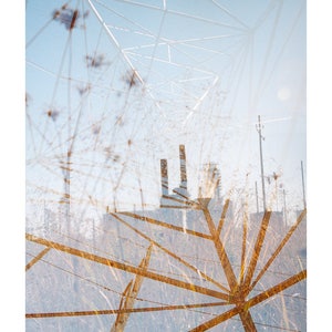 May include: A double exposure photograph of a power line structure with a factory in the background. The power line structure is made of metal and is in the foreground of the image. The factory is in the background and is partially obscured by the power line structure. The image is in a light blue and brown color scheme.