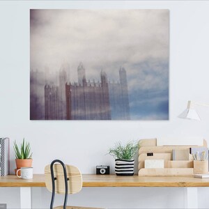 May include: A photograph of a tall building with a cloudy sky in the background. The building is tall and narrow, with many windows. The sky is a light blue color, with white clouds.