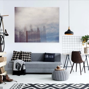 May include: A living room interior with a gray sofa, a black and white patterned rug, a black pendant light, a potted plant, and a framed print of a city skyline in the fog.