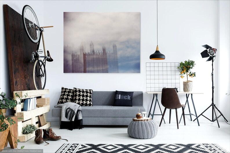 May include: A living room interior with a gray sofa, a black and white patterned rug, a black pendant light, a potted plant, and a framed print of a city skyline in the fog.