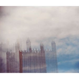 May include: A tall building with a gothic architecture style is partially obscured by a thick layer of fog. The building is made of stone and has many windows. The fog is white and dense, and it creates a mysterious and ethereal atmosphere.