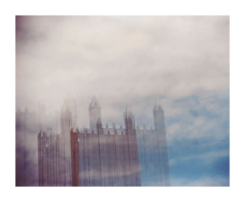 May include: A tall building with a gothic architecture style is partially obscured by a thick layer of fog. The building is made of stone and has many windows. The fog is white and dense, and it creates a mysterious and ethereal atmosphere.