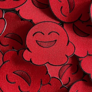 May include: Red felt patches with smiling faces in the shape of clouds. The patches are stitched together and have black outlines.