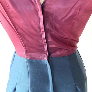 May include: A vintage dress featuring a burgundy silk bodice and a dark teal skirt. The bodice has a V-neckline and a zipper closure down the front. The skirt is a solid color with a tailored fit.