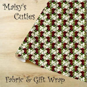 May include: A roll of fabric or gift wrap featuring a repeating pattern of red and white roses with green foliage on a white background. The words "Maisy's Cuties" and "Fabric & Gift Wrap" are printed on the image.