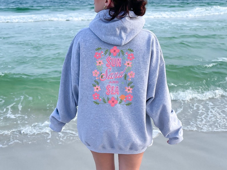 May include: Gray hooded sweatshirt with a floral design and the text "Sun Sand and Sea" on the back.